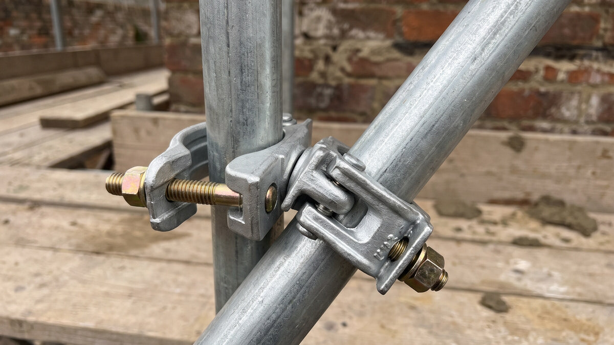 Galvanised swivel coupler joining a diagonal brace tube to a scaffold standard