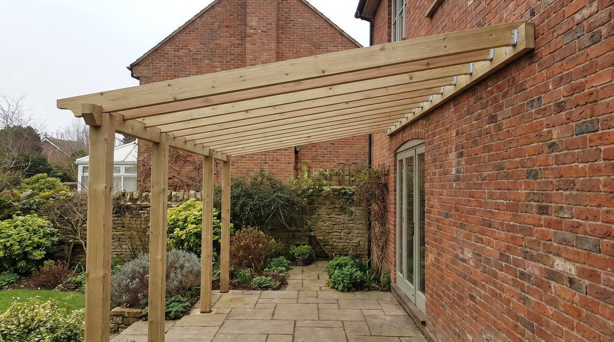Wall-mounted lean-to timber pergola fixed to a red brick house wall with galvanised steel brackets, posts standing on the paved terrace